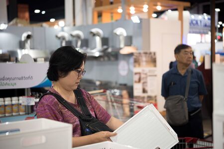 Bangkok, Thailand - March 23, 2019 : Unidentified asian woman feeling happy when her purchase a big product with cartons in shopping cart in department store or exhibit hall expoのeditorial素材