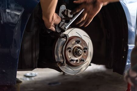 Car mechanic or serviceman checking a disc brake and asbestos brake pads it's a part of car use for stop the car for safety at front wheel this a new spare part for repair at car garageの写真素材