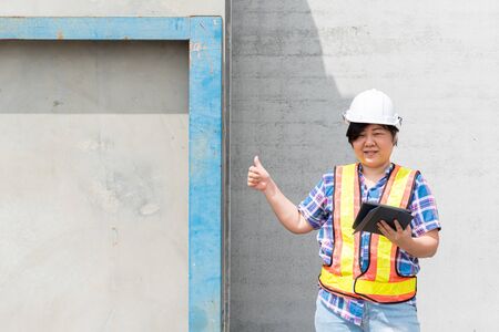 Asian woman civil construction engineer worker or architect with helmet and safety vest working and...