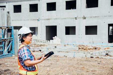 Asian woman civil construction engineer worker or architect with helmet and safety vest working and...