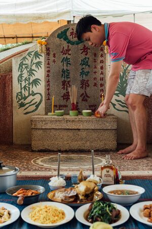 Prachinburi, Thailand - April 7, 2019 : Thai Chinese respect ancestors parents those died by food and burn fake money to sacrifice them at cemetery in Qingming Festival (Qing Ming), Tomb-Sweeping Dayのeditorial素材