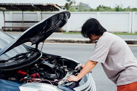 Asian woman 40s alone driver checking a car engine for fix and repair problem with unhappy and...
