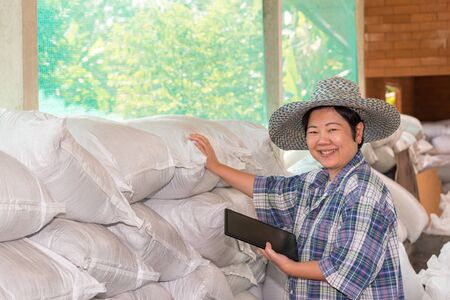 Asian woman smart farmer agriculturist happy at a Fertilizer composting plant with Organic Fertilizer, Compost (Aerobic Microorganisms) from animal waste for use in the organic agriculture industryの写真素材