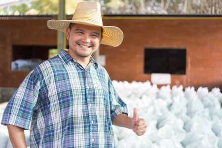 Asian man farmer agriculturist happy thumbs up at a Fertilizer composting plant with Organic Fertilizer, Compost (Aerobic Microorganisms) from animal waste for use in the organic agriculture industryの写真素材