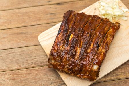 Roasted Pork Spare Ribs Barbecue or Pork Ribs with BBQ Sauce on wooden cutting board in kitchen at...