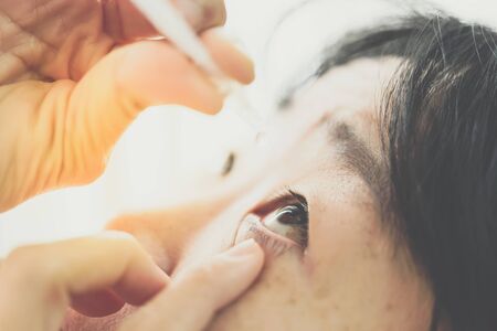 Asian woman use eye drop or artificial tears by drops in to the eye for inflammation or dryness problem therapy of eyeball for eyes healthの写真素材