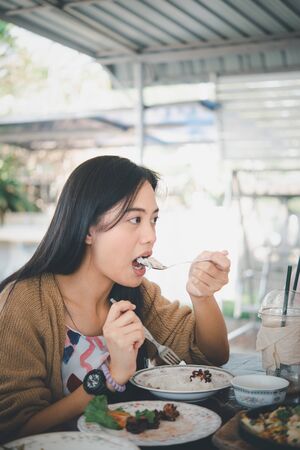 Asian pretty cute woman eating thai food with rice and many food on dining table in restaurant with happy and enjoy emotionの写真素材