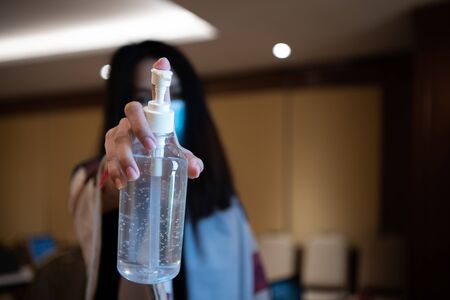 Asian woman wearing mask and alcohol antibacterial hand gel respiratory protection mask against epidemic flu covid19 or corona virus with fear emotion in concept illness, outbreak, healthcare in lifeの写真素材