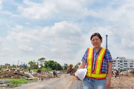 Asian woman civil construction engineer worker or architect with helmet and safety vest happy...