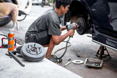 Bangkok, Thailand - February 15, 2020 : Unidentified car mechanic or serviceman disassembly and checking a disc brake and asbestos brake pads for fix and repair problem at car garage or repair shopのeditorial素材