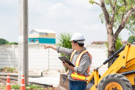 Asian man civil construction engineer worker or architect with helmet and safety vest working and...