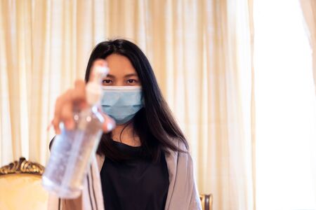 Asian woman wearing mask and alcohol antibacterial hand gel respiratory protection mask against epidemic flu covid19 or corona virus with fear emotion in concept illness, outbreak, healthcare in lifeの写真素材