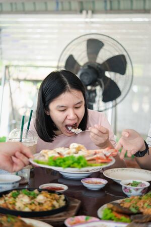 Asian pretty cute woman eating thai food with rice and many food on dining table in restaurant with happy and enjoy emotionの写真素材