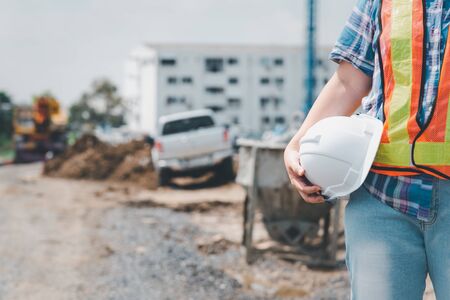 Asian woman civil construction engineer worker or architect with helmet and safety vest happy working at a building or construction siteの写真素材