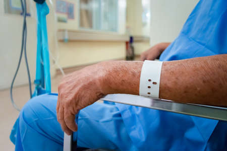 Patient asian elder man 70s with saline intravenous at C-line or A-line on a elderly patient hand on patient bed in intensive care unit (ICU.) room at hospital.の写真素材