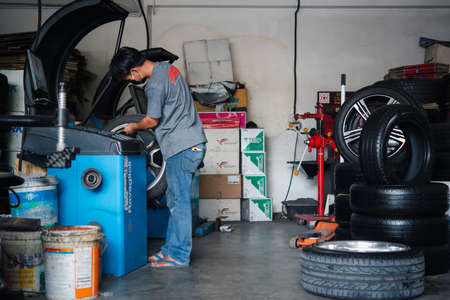Bangkok, Thailand - April 4, 2020 : Unidentified car mechanic or serviceman wheel alignment and tire balance checking car wheel for fix and repair suspension problem at car garage or repair shopのeditorial素材