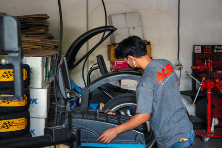 Bangkok, Thailand - April 4, 2020 : Unidentified car mechanic or serviceman wheel alignment and tire balance checking car wheel for fix and repair suspension problem at car garage or repair shopのeditorial素材