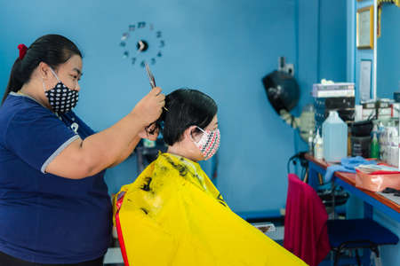 Bangkok, Thailand - May 16, 2020 : Unidentified asian woman hairdresser or hairstyle haircut a woman plump body customer in fashion hairstyle at barbershopのeditorial素材