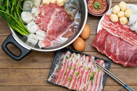 Cooking food by put a flesh beef, pork, egg and vegetable in to a hot pot for make a sukiyaki or shabu at japanese shabu buffet restaurantの写真素材