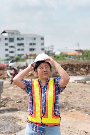 Asian woman civil construction engineer worker or architect with helmet and safety vest happy...