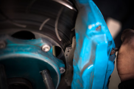 Car mechanic or serviceman disassembly and checking a disc brake and asbestos brake pads for fix and repair problem at car garage or repair shopの写真素材