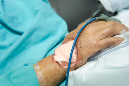 Patient asian elder woman 80s flu covid19 with pulse gauge for heartbeat measuring and blood pressure on a patient elderly finger on patient bed in intensive care unit (ICU.) room at hospitalの写真素材