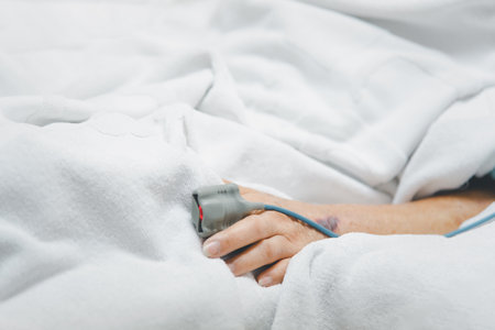 Patient asian elder woman 80s flu covid19 with pulse gauge for heartbeat measuring and blood pressure on a patient elderly finger on patient bed in intensive care unit (ICU.) room at hospitalの写真素材