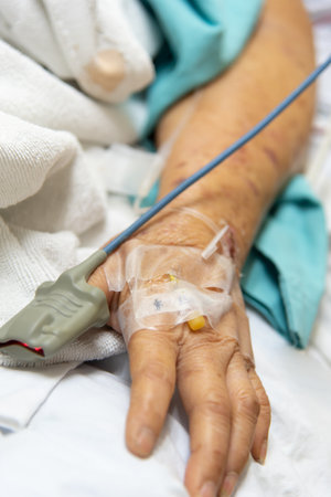 Patient asian elder woman 80s flu covid19 with pulse gauge for heartbeat measuring and blood pressure on a patient elderly finger on patient bed in intensive care unit (ICU.) room at hospitalの写真素材