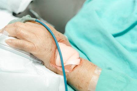 Patient asian elder woman 80s flu covid19 with pulse gauge for heartbeat measuring and blood pressure on a patient elderly finger on patient bed in intensive care unit (ICU.) room at hospitalの写真素材