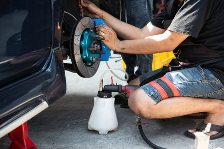 Bangkok, Thailand - March 6, 2021 : Unidentified car mechanic or serviceman disassembly and checking a disc brake and asbestos brake pads for fix and repair problem at car garage or repair shopの写真素材
