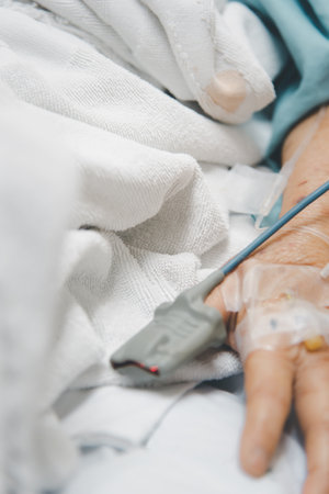 Patient asian elder woman 80s flu covid19 with pulse gauge for heartbeat measuring and blood pressure on a patient elderly finger on patient bed in intensive care unit (ICU.) room at hospitalの写真素材