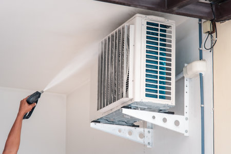 Worker to cleaning coil cooler of air conditioner by water for clean a dust on the wall in customer home when maintenance serviceの写真素材