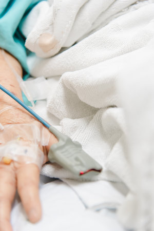 Patient asian elder woman 80s flu covid19 with pulse gauge for heartbeat measuring and blood pressure on a patient elderly finger on patient bed in intensive care unit (ICU.) room at hospitalの写真素材