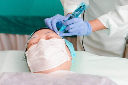 Asian woman eyebrow tattooing by doctor specialist in Eyebrow tattoo clinic or Eyebrow embroidery clinic for tattoo or correction use COVID-19 prevention policy protect by use mask and face shieldの写真素材