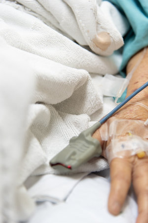 Patient asian elder woman 80s flu covid19 with pulse gauge for heartbeat measuring and blood pressure on a patient elderly finger on patient bed in intensive care unit (ICU.) room at hospitalの写真素材