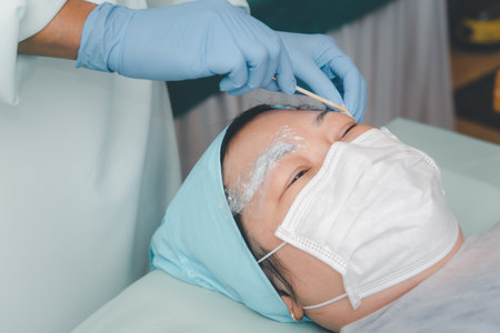 Asian woman eyebrow tattooing by doctor specialist in Eyebrow tattoo clinic or Eyebrow embroidery clinic for tattoo or correction use COVID-19 prevention policy protect by use mask and face shieldの写真素材