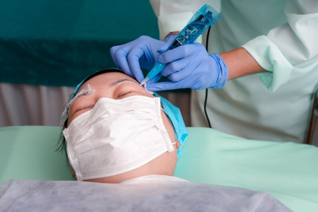Asian woman eyebrow tattooing by doctor specialist in Eyebrow tattoo clinic or Eyebrow embroidery clinic for tattoo or correction use COVID-19 prevention policy protect by use mask and face shieldの写真素材