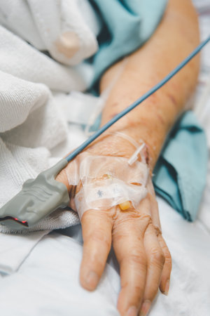Patient asian elder woman 80s flu covid19 with pulse gauge for heartbeat measuring and blood pressure on a patient elderly finger on patient bed in intensive care unit (ICU.) room at hospitalの写真素材