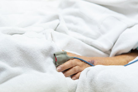 Patient asian elder woman 80s flu covid19 with pulse gauge for heartbeat measuring and blood pressure on a patient elderly finger on patient bed in intensive care unit (ICU.) room at hospitalの写真素材