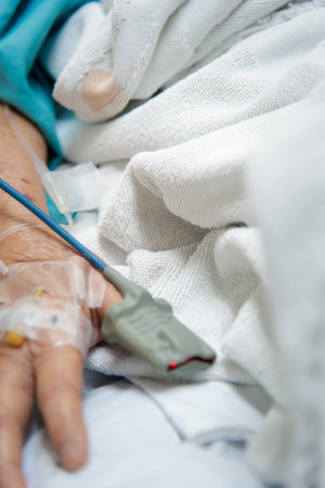 Patient asian elder woman 80s flu covid19 with pulse gauge for heartbeat measuring and blood pressure on a patient elderly finger on patient bed in intensive care unit (ICU.) room at hospitalの写真素材