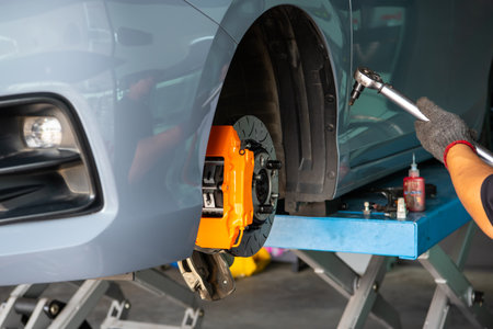 Car mechanic or serviceman disassembly and checking a disc brake and asbestos brake pads for fix and repair problem at car garage or repair shopの写真素材