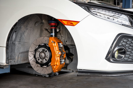 Car mechanic or serviceman disassembly and checking a disc brake and asbestos brake pads for fix and repair problem at car garage or repair shopの写真素材