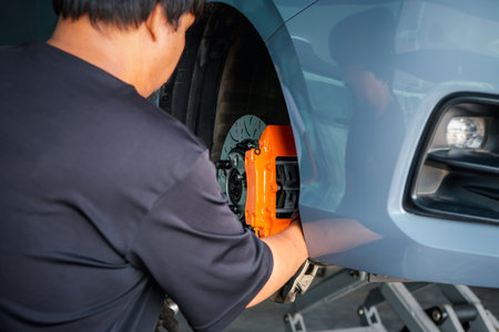 Car mechanic or serviceman disassembly and checking a disc brake and asbestos brake pads for fix and repair problem at car garage or repair shopの写真素材