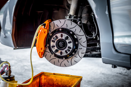 Car mechanic or serviceman disassembly and checking a disc brake and asbestos brake pads for fix and repair problem at car garage or repair shopの写真素材