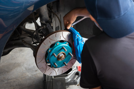 Car mechanic or serviceman disassembly and checking a disc brake and asbestos brake pads for fix and repair problem at car garage or repair shopの写真素材
