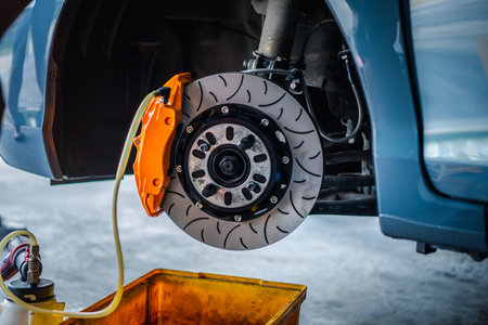 Car mechanic or serviceman disassembly and checking a disc brake and asbestos brake pads for fix and repair problem at car garage or repair shopの写真素材