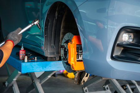 Car mechanic or serviceman disassembly and checking a disc brake and asbestos brake pads for fix and repair problem at car garage or repair shopの写真素材