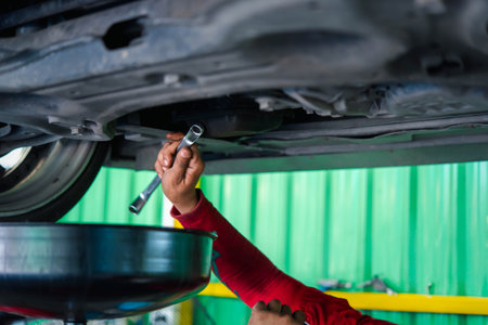 Car mechanic drain the old lubricant engine oil at car garage for changing the oil in a car engineの写真素材