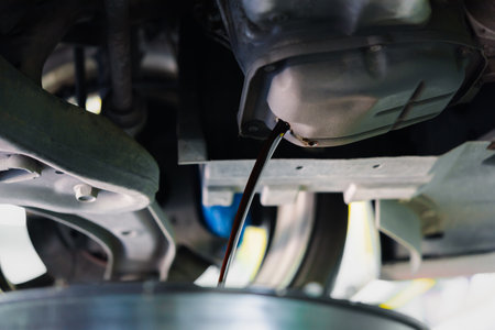 Car mechanic drain the old lubricant engine oil at car garage for changing the oil in a car engineの写真素材