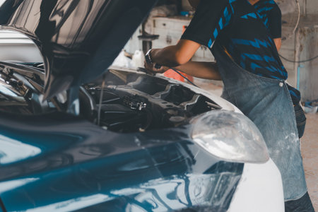 Denter or car mechanic serviceman check and fix body work and fiber bumper body part for fix and repair problem at car garage or repair shopの写真素材